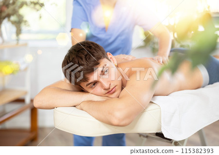 Female massagist doing massage to male client in spa center Female massagist doing massage to male client in spa center 115382393