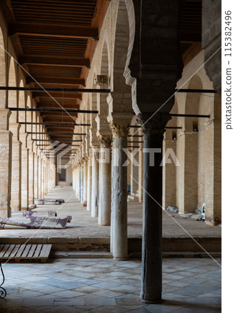Long corridors under vaulted ceiling in ancient mosque of Kairouan in Tunisia. 115382496