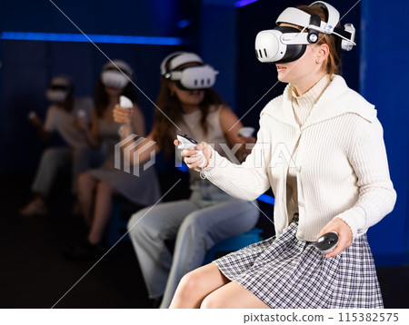 Expressive girl in VR goggles having fun in virtual reality room 115382575