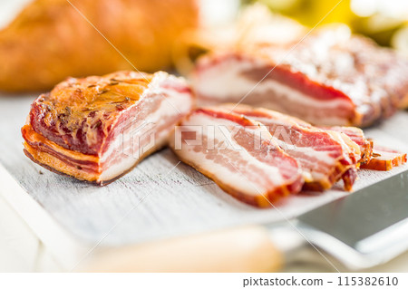 Closeup of Sliced Smoked Bacon on white Cutting Board 115382610