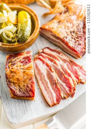 Closeup of Sliced Smoked Bacon on white Cutting Board 115382611