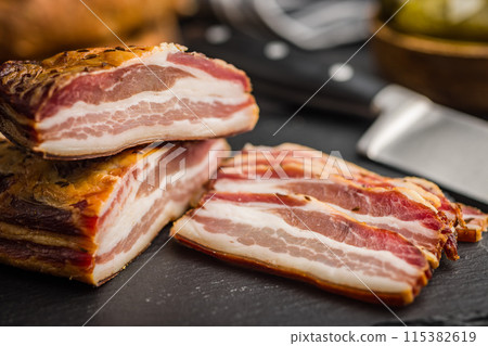Closeup of Sliced Smoked Bacon on Black Slate Cutting Board Closeup of Sliced Smoked Bacon on Black Slate Cutting Board 115382619