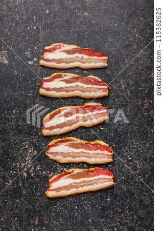Five Strips of Raw Bacon on a Dark Grey Countertop. Top view. Five Strips of Raw Bacon on a Dark Grey Countertop. Top view. 115382625