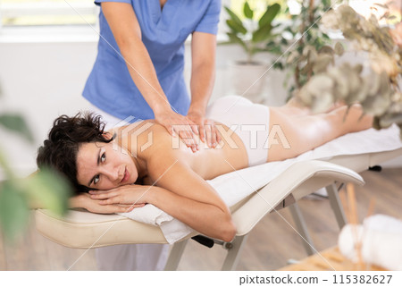 Portrait of woman relaxing on massage table at spa center 115382627