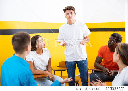 Male student discussing with groupmates sitting in circle in auditorium during classes Male student discussing with groupmates sitting in circle in auditorium during classes 115382651