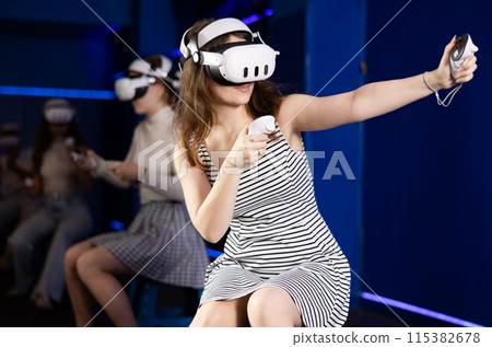 Expressive girl in VR goggles having fun in virtual reality room 115382678