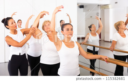 Dancing women stand in a ballet stance, where the choreographer helps to coordinate the movement Dancing women stand in a ballet stance, where the choreographer helps to coordinate the movement 115382681