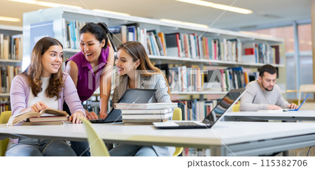 Three female friends studying together at library Three female friends studying together at library 115382706