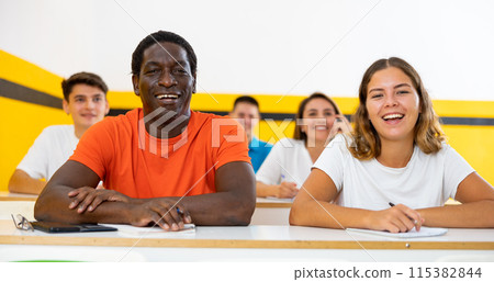 Cheerful smiling adult students at their desks in university classroom 115382844