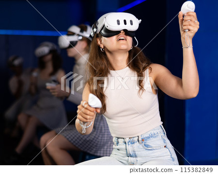 Expressive girl in VR goggles having fun in virtual reality room 115382849