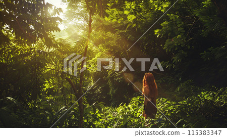 a solitary  figure standing in the midst of a lush forest, their face illuminated by the soft glow of sunlight filtering through the canopy above 115383347