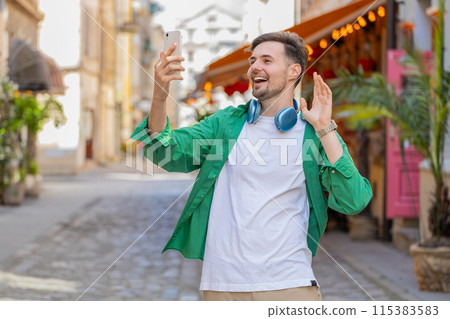 Happy man blogger taking selfie on smartphone communicating video call online with subscribers Happy man blogger taking selfie on smartphone communicating video call online with subscribers 115383583