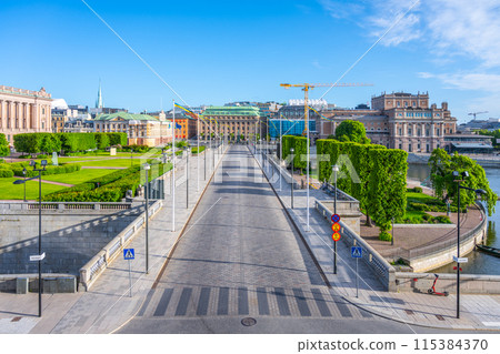 A clear blue sky shines over Riksplan Park in Stockholm, showcasing the vibrant greenery and the architectural splendor that lines the tranquil paths. Sweden A clear blue sky shines over Riksplan Park in Stockholm, showcasing the vibrant greenery and the architectural splendor that lines the tranquil paths. Sweden 115384370