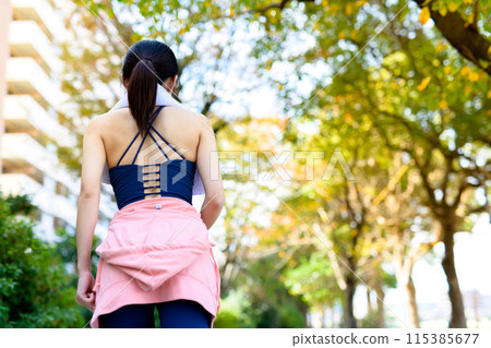 一位年輕女子在秋季公園的樹叢中慢跑的後視圖、飲食、身體化妝 115385677