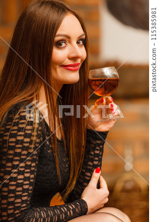 Woman tasting wine in rural cottage interior 115385981