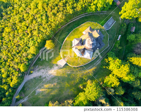 Aerial view of the Church of Saint John the Baptist and Our Lady of Mount Carmel at Makova hora in Czechia, surrounded by lush green trees on a summer day. Aerial view of the Church of Saint John the Baptist and Our Lady of Mount Carmel at Makova hora in Czechia, surrounded by lush green trees on a summer day. 115386308