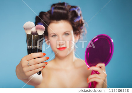 woman in hair rollers holds makeup brushes woman in hair rollers holds makeup brushes 115386328
