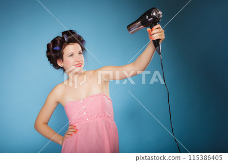 girl with curlers in hair holds hairdreyer 115386405
