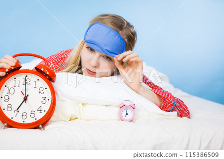 Sleeping woman wearing pajamas holding clock Sleeping woman wearing pajamas holding clock 115386509