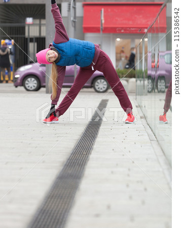 Sporty girl stretching outdoor on city street. 115386542
