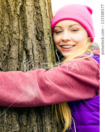 Woman wearing sportswear hugging tree 115386577