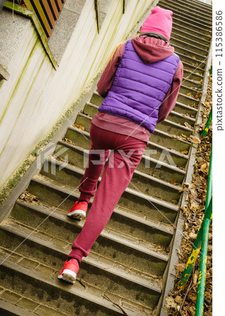 Woman wearing sportswear exercising outside during autumn 115386586