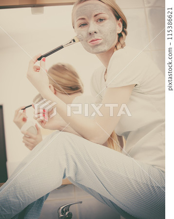 Woman applying with brush clay mud mask to her face 115386621