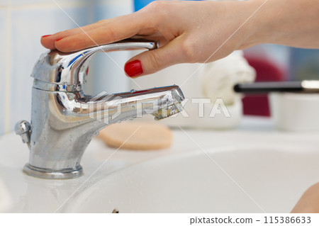 Woman washing hands under flowing tap water in the bathroom Woman washing hands under flowing tap water in the bathroom 115386633