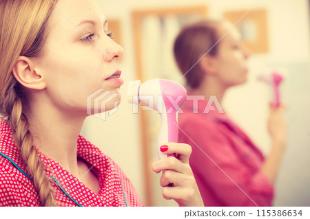 Woman using facial cleansing brush on face Woman using facial cleansing brush on face 115386634