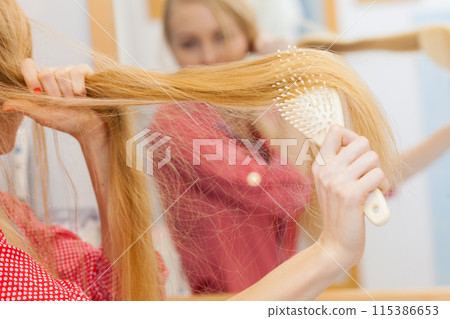 Woman brushing her long hair in bathroom Woman brushing her long hair in bathroom 115386653