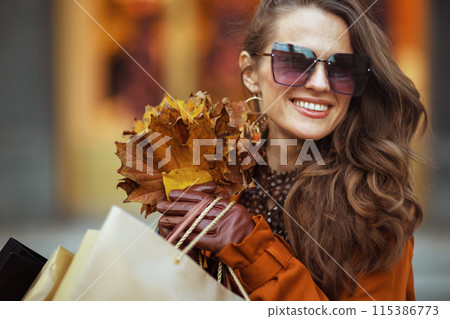 happy stylish woman in orange trench coat with shopping bags happy stylish woman in orange trench coat with shopping bags 115386773