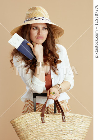 sad stylish woman in blouse and shorts on beige 115387276