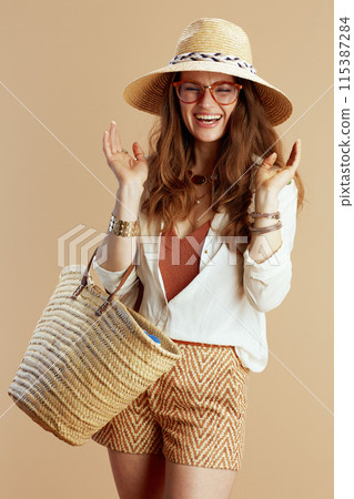 happy elegant woman in blouse and shorts against beige 115387284
