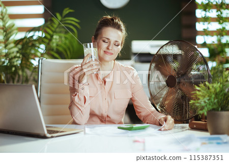 happy modern woman worker at work with electric fan and laptop 115387351