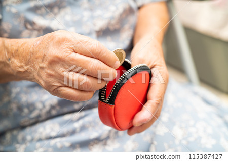 Asian senior woman holding counting coin money in purse. Poverty, saving problem in retirement. 115387427