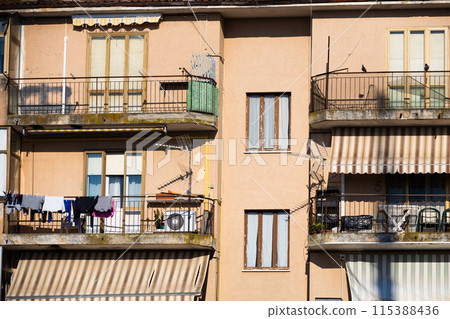 Old block of flats building exterior with laundry on the balcony lit with sun, Grado, Italy 115388436
