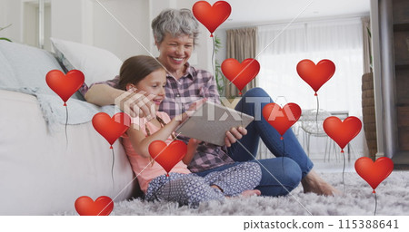 Image of heart balloons over happy caucasian grandmother and granddaughter using tablet at home Image of heart balloons over happy caucasian grandmother and granddaughter using tablet at home 115388641