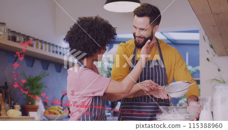 Image of hearts over diverse couple preparing meal in kitchen 115388960
