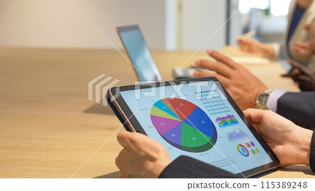 Business people having a meeting while looking at a tablet screen 115389248