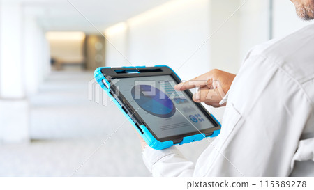 Engineer checking a building while looking at a tablet Engineer checking a building while looking at a tablet 115389278