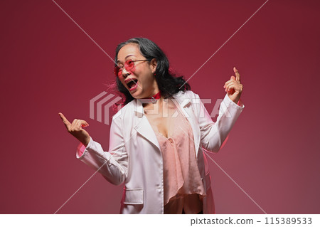 Active middle age woman dancing having fun isolated on red background 115389533