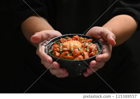 Chef holding bowl of delicious salmon don with pickled egg yolk on black background Chef holding bowl of delicious salmon don with pickled egg yolk on black background 115389557