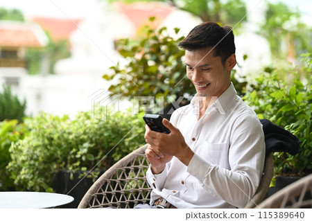 Smiling businessman using mobile phone on cafe terrace Smiling businessman using mobile phone on cafe terrace 115389640