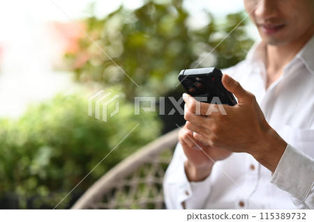 Cropped shot of businessman using mobile phone while sitting at an outdoor cafe Cropped shot of businessman using mobile phone while sitting at an outdoor cafe 115389732