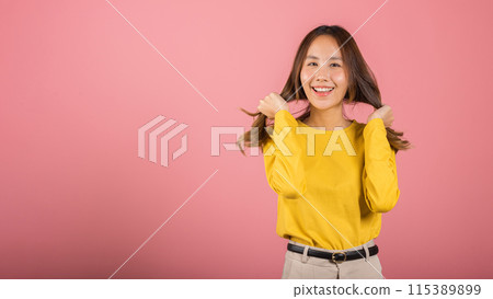 Portrait Asian attractive young woman wearing a yellow shirt with long hair is smiling and holding her hair back in studio shot isolated on pink background, so happy and funny cute girl Portrait Asian attractive young woman wearing a yellow shirt with long hair is smiling and holding her hair back in studio shot isolated on pink background, so happy and funny cute girl 115389899