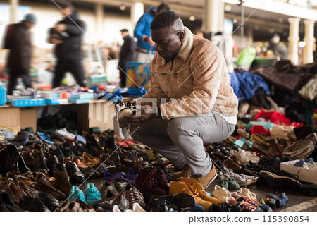 Ordinary african american guy sells sacond hands shoes at flea market 115390854