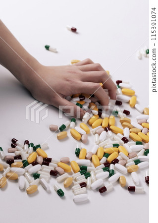 holding a handful of pills with one's hand 115391074