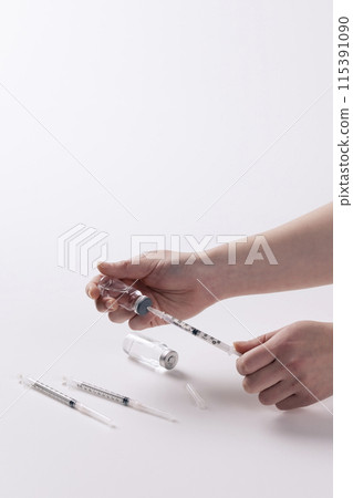putting a syringe in an injection bottle 115391090