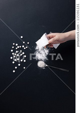 a hand holding a plastic bag containing drugs a hand holding a plastic bag containing drugs 115391131