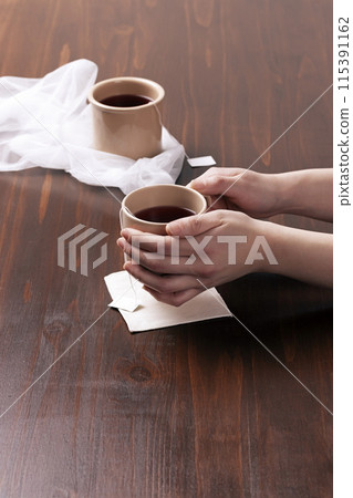 Covering a mug of tea bags with both hands 115391162